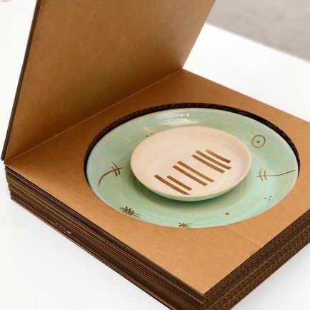 Caja de cartón con tapa y un hueco que contiene un plato